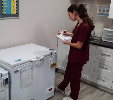 Nurse with clipboard next to the TempArmour Vaccine Refrigerator (Model BFRV84)