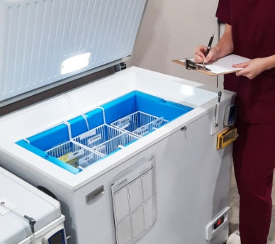 Nurse with clipboard next to the TempArmour Vaccine Refrigerator (Model BFRV84)
